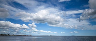 Beyaz kabarık bulutlar mavi gökyüzünde Büyük güney körfezi köprüsü arka planda Babil Long Island körfezi üzerinde.