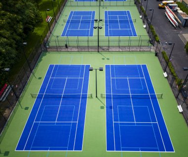 Altı tenis kortuna bakıyorum. Pickleball için sıralanmış mavi ve yeşil yüzeyi ve geceleri oynamak için ışıkları var..