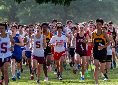 Kings Park, New York, ABD - 15 Eylül 2023: Long Island, New York 'taki Sunken Meadow State Park' ta 5K 'lık bir kros yarışının başında koşan büyük bir lise öğrencisinin ön görüntüsü.