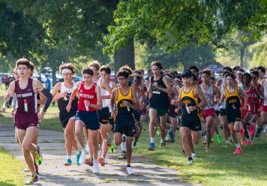 Kings Park, New York, ABD - 15 Eylül 2023: Long Island, New York 'taki Sunken Meadow State Park' ta 5K 'lık bir kros yarışının başında koşan büyük bir lise öğrencisinin ön görüntüsü.