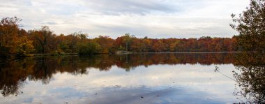 Ekim ayı sonlarında Babil Village Long Island New York 'ta yer alan Güney Gölü' nü çevreleyen renkli ağaçlar panoraması.