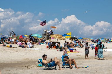 Babil, New York, ABD - 24 Temmuz 2021: İnsanların ahenkli bir araya gelmesi teselliyi ve sevinci, Fire Island New York 'taki kumsalın sıcak taneciklerine tünemiş olarak buldu.