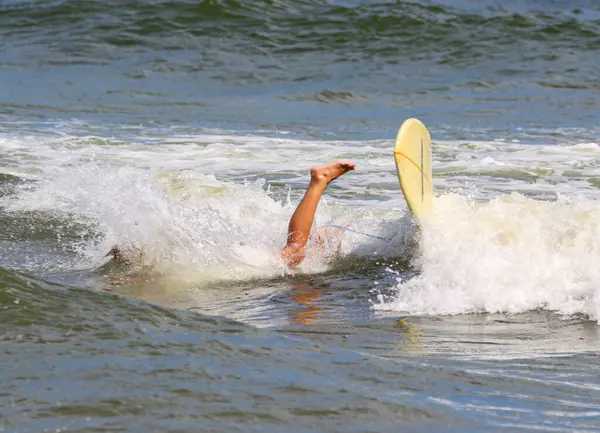 One Leg sticking out of the water after a surfer falls of surboard while surfing off the coast of Long Island.