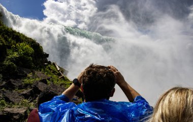 Tourists looking up and taking pictures of American Falls in Niagara Falls New York. clipart