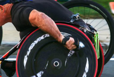 Maraton sırasında tekerlekli sandalyede yarışan bir adamın yan görüntüsü..