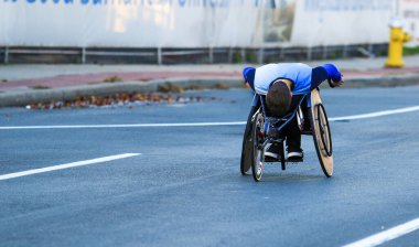 Tekerlekli sandalyedeki bir genç New York 'taki Long Island maratonunda yarışırken yolun aşağısına taşınıyor..