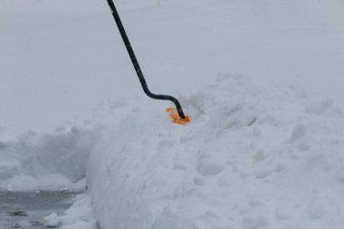 Kar küreği, kar fırtınası sırasında bir garaj yolunun yanında kürekle temizleniyor..