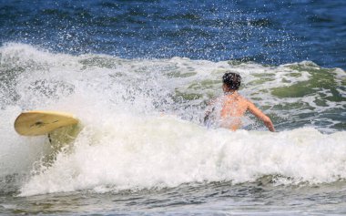 Long Island sahilindeki Gilgo Plajı 'nda sörf yaparken sörf tahtasından düşen genç bir adam..