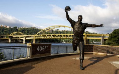 Pittsburgh, Pennsylvania, ABD - 8 Ağustos 2023: Arka planda sarı ve altın köprüler bulunan Pittsburgh şehrindeki PNC Field 'daki Bill Mazeroski heykelinin ön görüntüsü.