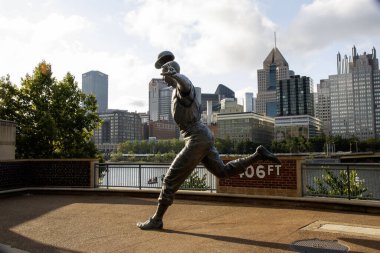 Pittsburgh, Pennsylvania, USA - 8 August 2023: Side view of the Bill Mazeroski Statue at PNC Field in with the city of Pittsburgh Pennsylvania in the background. clipart