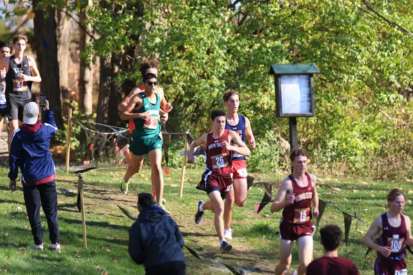 stock image Wappinger Falls, New York, USA - 18 November 2023: High School boys running out of the woods on a downhill in the middle of a 5K rcross country race in Bowdoin Park.