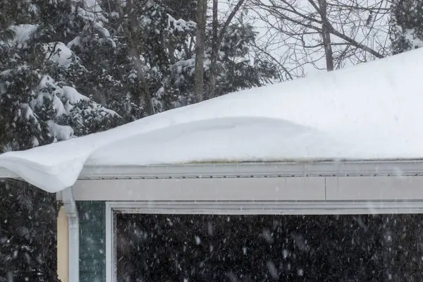 Stock image Snow is piling on the roof of a house as the snow is still falling during a blizzard on Long Island in New York.