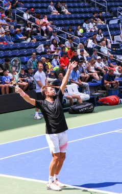 Queens New York, ABD - 20 Ağustos 2024: Taraftarlar ABD Açık tribünlerinden hevesle izlerken, bir tenisçi parlak bir günde antrenman yapmaya hazırlanıyor.