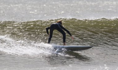 Giglo Sahili 'nde siyah dalış kıyafeti giymiş sörf yapan bir erkeğin yan görüntüsü..