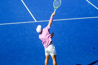 Güneşli bir öğleden sonra tenis maçında top servis eden bir adamın yukarıdan görünüşü..