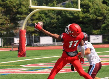 Close up of a high school football Wide receiver making a one handed catch in the end zone during a football game from behind. clipart