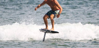 Close up of a shirtless man hydrofoiling on a kite board in the Atlantic Ocean. clipart