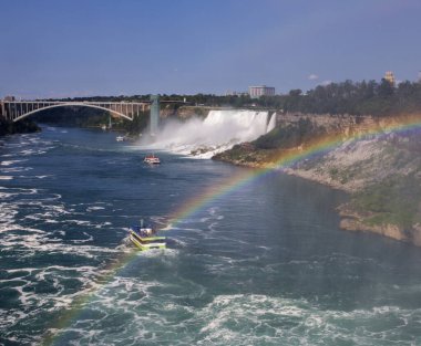 Turistler şelalenin üzerinden gökkuşağına bakarken tekne gezintisinin tadını çıkarırlar..