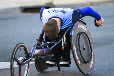 Babylon, New York, ABD - 22 Ekim 2023: Kararlı bir sporcu yarış tekerlekli sandalyesiyle bir sokak pistinde yol alıyor, yeteneğini ve dikkatini gösteriyor.