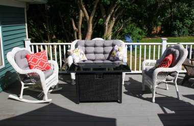 Rahat bir güvertede dekoratif yastıkları ve şık bir masası olan yastıklı bir oturma alanı vardır..