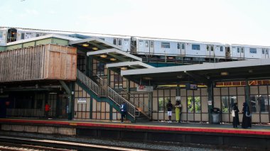 Woodside, New York, ABD - 20 Ağustos 2024: Çok sayıda tren hareketli bir şehir istasyonunda hareket ediyor, parlak güneş ışığı manzarayı aydınlatıyor