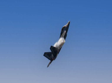 Jones Beach, New York, ABD - 29 Mayıs 2022: Pürüzsüz, gri bir F-35 Lightning II savaş uçağı, kanatlarında buhar konisiyle mavi gökyüzünde uçuyor..