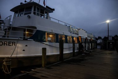 Mürettebattan oluşan büyük bir feribot, akşam vakti sıcak ışıklarla aydınlanan bir rıhtıma yanaşır..