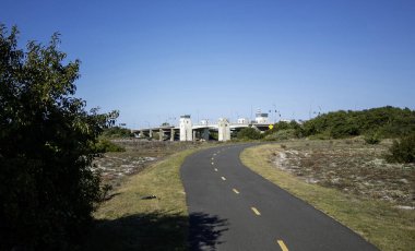 Yeşillikle çevrili dolambaçlı bir yol, güneşli bir günde barışçıl bir atmosfer yaratan asma bir köprüye yaklaşıyor..