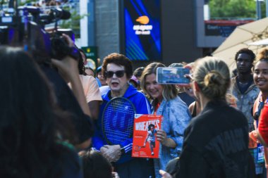 Queens, New York, ABD - 20 Ağustos 2024: Billie Jean King canlı bir spor etkinliğinde elinde tenis raketi tutan taraftarlarla neşe içinde etkileşim kuruyor.