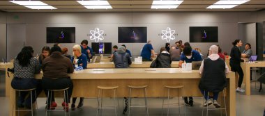 Huntington, New York, ABD - 1 Mayıs 2022: Müşteriler bir Apple mağazasındaki perakende satış personeliyle geniş bir teknoloji mağazasında elektronik ürünleri incelerken etkileşim halindeler.