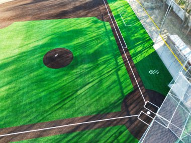 Canlı yeşil çimenler ve açık işaretli yeni kurulmuş yapay çim beyzbol sahasının havadan görünüşü.