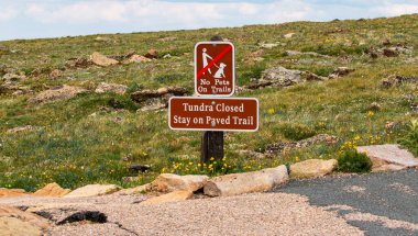 Tundra bölgesinde evcil hayvanların patikalarda gezmesini yasaklayan bir tabela ve Rocky Dağı Ulusal Parkı Colorado 'da asfalt yollarda kalmaları için uyarıcılar bulunuyor..