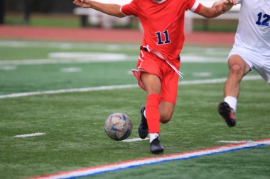 İki oyuncu sahada futbol topuna sahip olmak için çabalarken çarpışıyor..