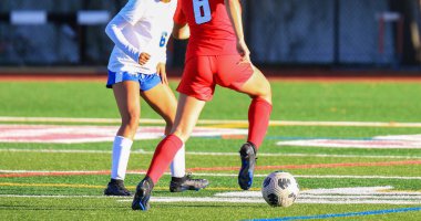 İki genç futbolcu sahada yeteneklerini sergilerken rekabetçi bir maç yapıyorlar..