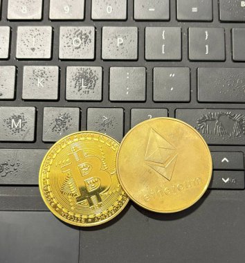 İki kripto para birimi, Bitcoin ve Ethereum, modern bir çalışma ortamında dizüstü bilgisayarın klavyesinde yatıyor..