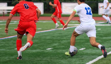 İki sporcu yoğun bir futbol maçında iyi korunmuş bir sahada yetenek ve kararlılık gösteriyorlar..