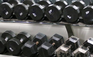 Ağırlıkların dambılları spor yapmak için spor salonunda bir askıya dizilmişti..