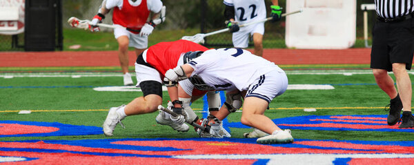 Two athletes engage in a face-off while a referee oversees the match.