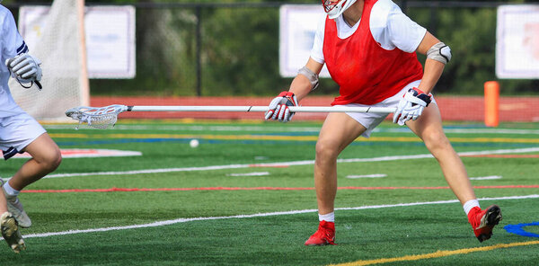 Two athletes practice lacrosse drills on a sunny afternoon on a turf field.