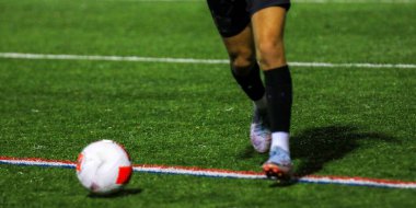 Bir oyuncu akşam maçı sırasında suni sahada topa vuruyor..