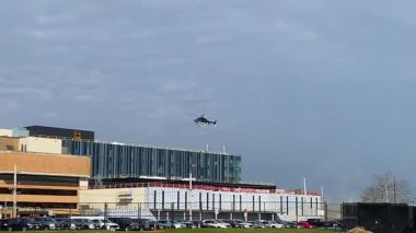 Bir helikopter hastanenin üzerinde alçaktan uçuyor ve inecek bir yer arıyor.