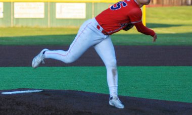Kendini adamış bir liseli atlet gün batımında canlı bir beyzbol sahasında atış yapıyor..