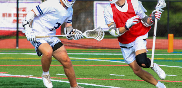 Two High School lacrosse players in battle during a game.