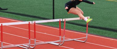 Yarışmacı, yarışmadan önce kırmızı bir pistte engelli atlama alıştırması yapıyor..