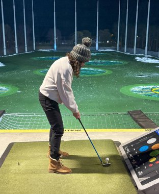 Golfçü gece parlak ışıkların altında golf sahasında sallanmaya hazırlanıyor..