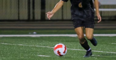 Oyuncu, iyi aydınlatılmış futbol sahasında kararlı bir vuruş yapmaya hazırlanıyor..
