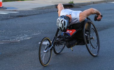 Kararlı bir atlet, bir yarışma sırasında şehir yollarında el bisikletini ileri itiyor.