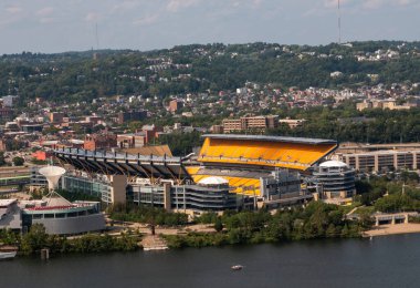 Pittsburgh, Pennsylvania, ABD - 8 Ağustos 2023: Nehir kıyısında canlı koltuklar ve şehrin ufuk çizgisi sergilenen parlak bir stadyum.