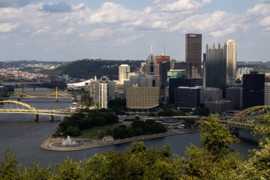 Pittsburgh, Pennsylvania, ABD - 8 Ağustos 2023: Pittsburgh şehir manzarasında mavi gökyüzü altında köprüler ve yeşil Point State parkları yer alıyor.