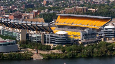 Pittsburgh, Pennsylvania, ABD - 8 Ağustos 2023: Boş sarı koltukları ve şehir binaları olan bir spor stadyumunun havadan görünüşü.